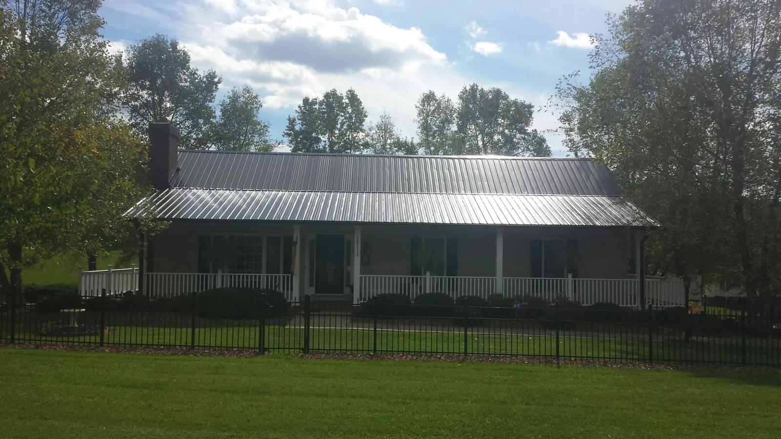 Gray metal roof on a brick ranch with a full width front porch — Gutter Guard Installation work by our crew in Enfield