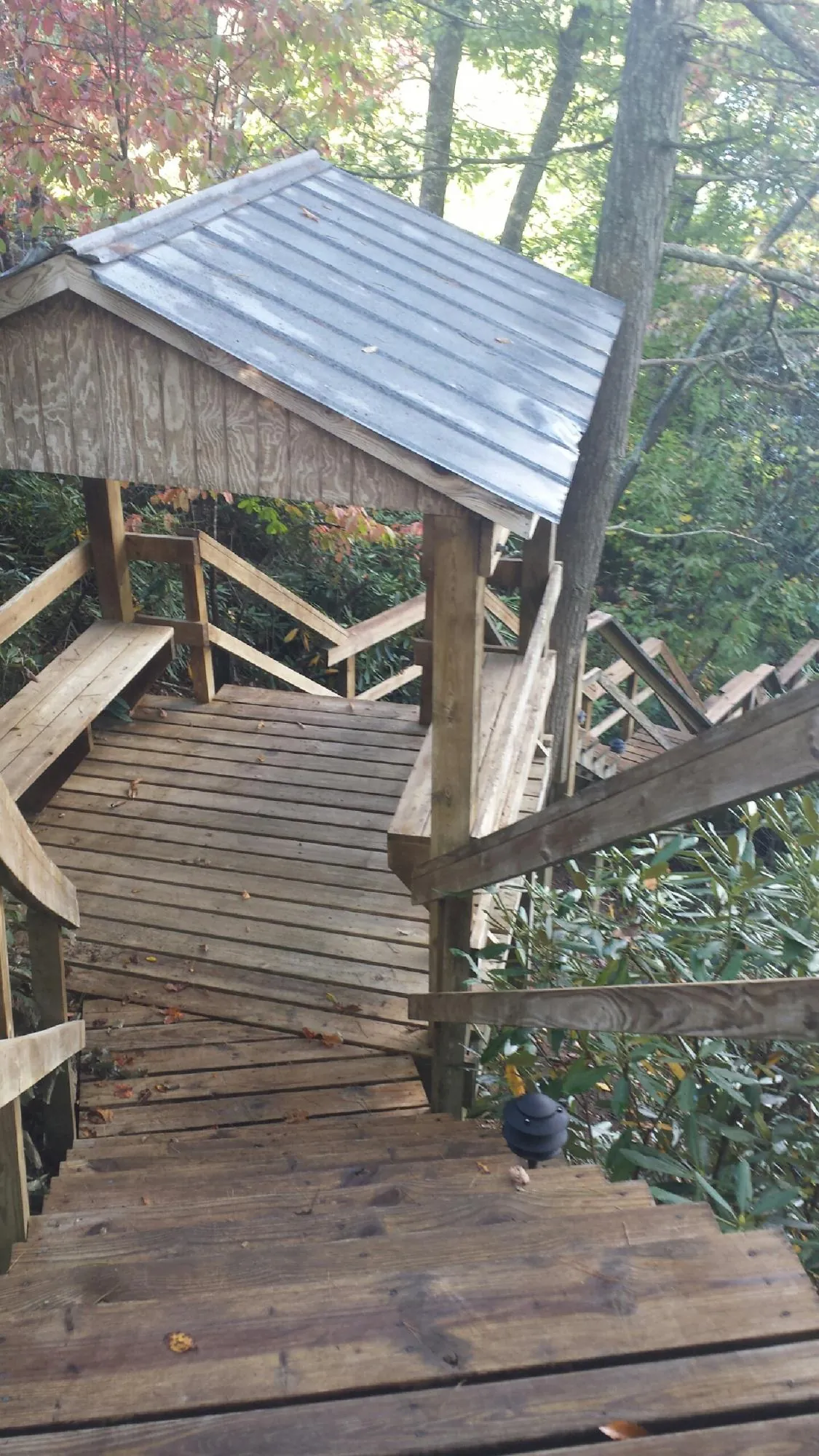 Metal roofed shelter over wooden steps on a wooded walkway — Skylight Repair & Installation work by our crew in Enfield