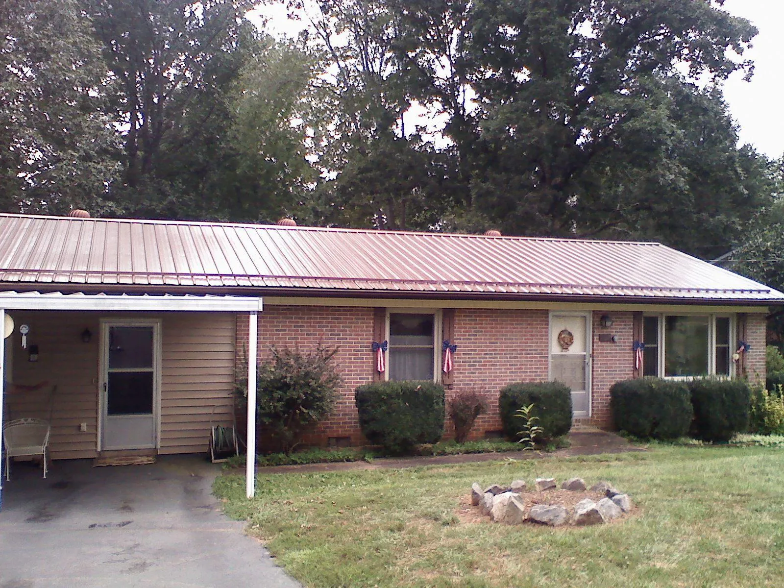 Bronze metal roof and carport on a brick ranch home — Roof Repair work by our crew in Enfield
